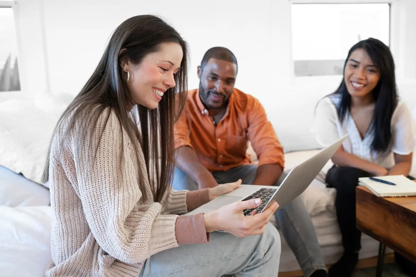 Группа молодых людей вместе использует ноутбук дома на диване.