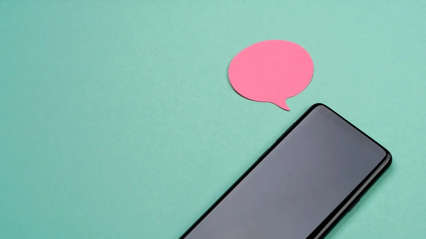 Композиция, снятая сверху, со смартфоном и самоклеящейся запиской.